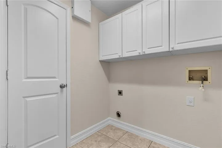 Laundry room featuring hookup for an electric dryer, washer hookup, cabinets, and light tile patterned floors