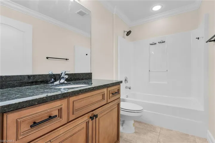 Full bathroom with ornamental molding, vanity, tub / shower combination, tile patterned flooring, and toilet