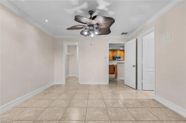 Spare room featuring light tile patterned floors, ceiling fan, and crown molding
