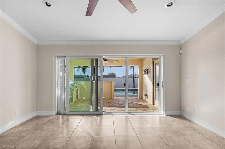 Tiled spare room featuring ornamental molding and ceiling fan