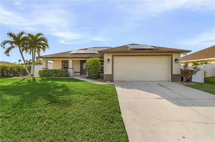 View of front of house featuring a garage, a front lawn, and solar panels