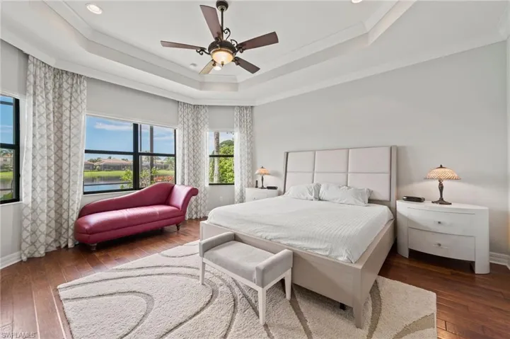 Bedroom with ceiling fan, a raised ceiling, crown molding, and dark hardwood / wood-style flooring