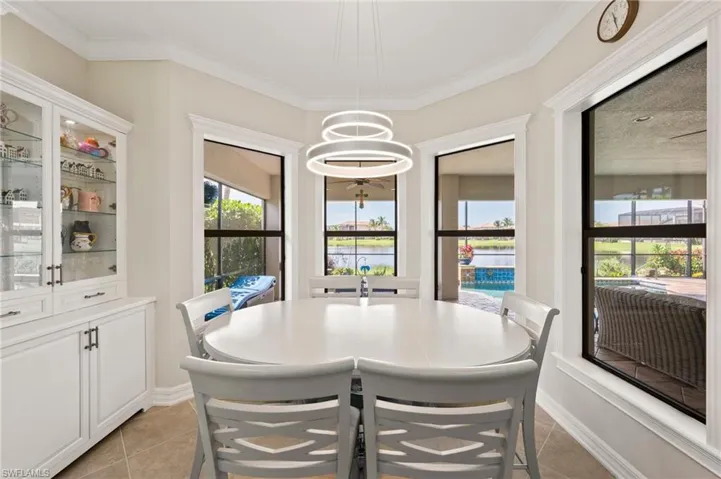 Tiled dining area featuring a notable chandelier, ornamental molding, and a wealth of natural light