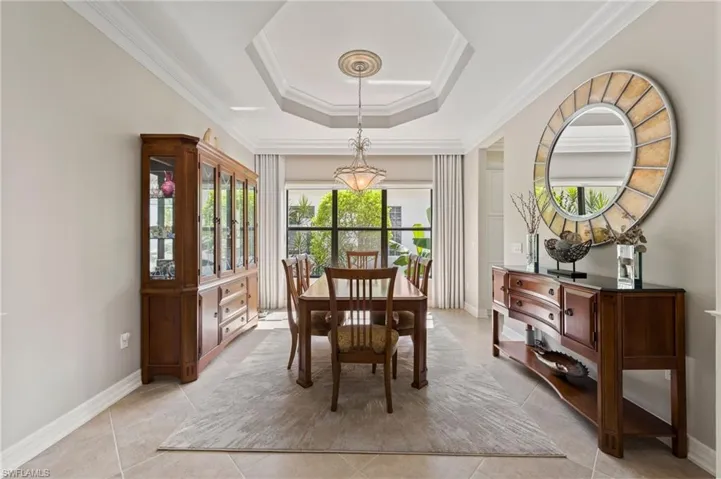 Tiled dining space with ornamental molding and a tray ceiling