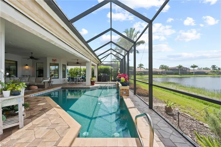 View of swimming pool with a water view, a patio, glass enclosure, and ceiling fan