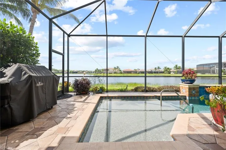 View of swimming pool featuring a lanai, a water view, and a patio area