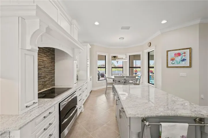 Kitchen with pendant lighting, white cabinets, light stone counters, and light tile patterned floors