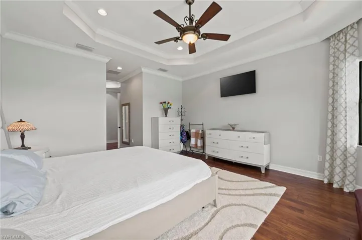 Bedroom featuring ornamental molding, a tray ceiling, ceiling fan, and dark hardwood / wood-style flooring
