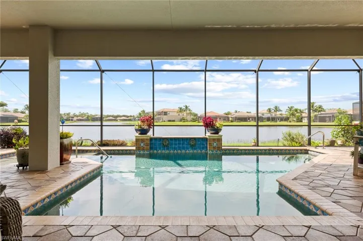 View of pool featuring a patio, glass enclosure, and a water view