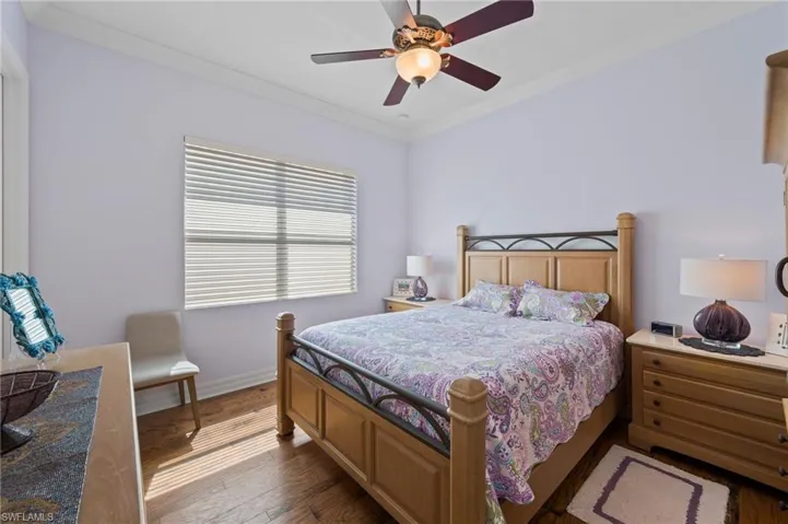 Bedroom with ornamental molding, ceiling fan, and dark hardwood / wood-style flooring
