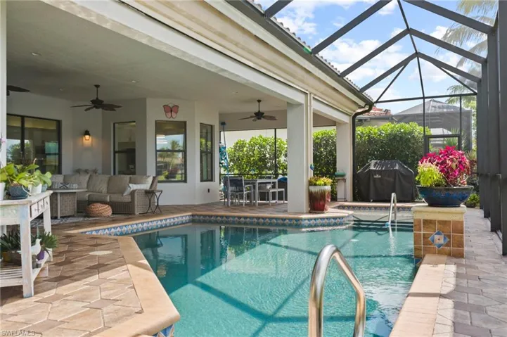 View of pool with a lanai, a patio, an outdoor living space, and ceiling fan