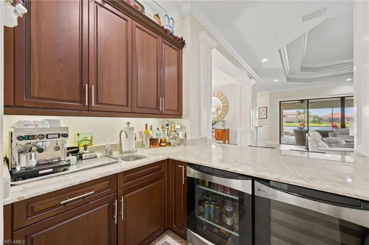 Kitchen featuring beverage cooler, crown molding, kitchen peninsula, and sink