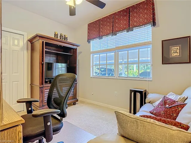 Carpeted home office with ceiling fan and baseboards
