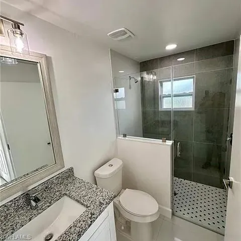 Full bathroom featuring tile patterned flooring, toilet, vanity, visible vents, and a stall shower
