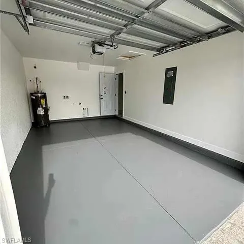 Garage featuring a garage door opener, electric panel, and water heater