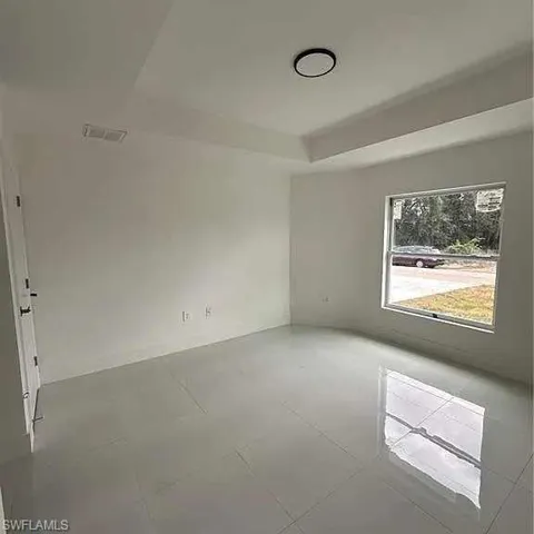 Empty room with a raised ceiling and visible vents