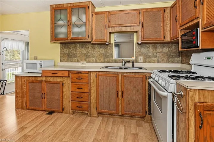 Kitchen featuring wood-finish cabinetry, light-toned countertops, and a tile backsplash