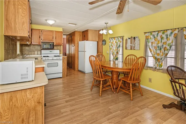 Kitchen featuring wood-finish cabinetry, white appliances, and a dining area with a chandelier