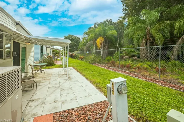 Covered patio with a tiled surface, bordered by a green lawn and mature landscaping
