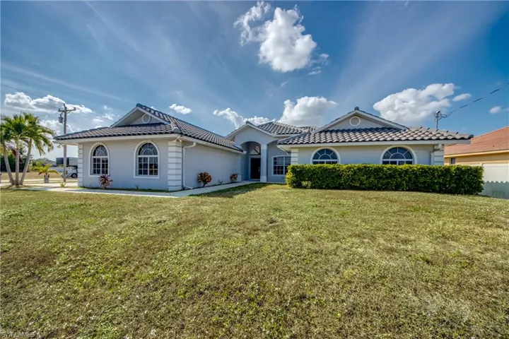 Mediterranean / spanish-style house with a front lawn, stucco siding, and a tiled roof