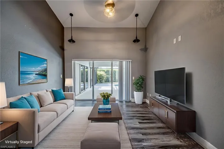 Living room featuring wood finished floors, a textured wall, and a high ceiling