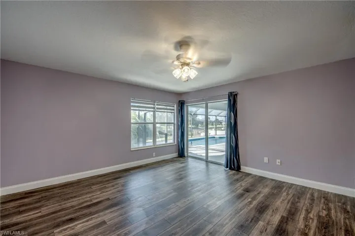 Unfurnished room featuring a ceiling fan, dark wood finished floors, and a textured ceiling