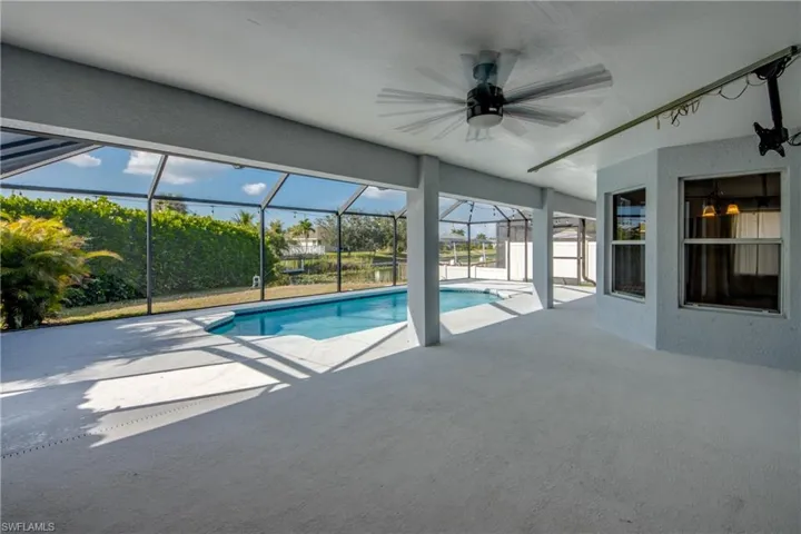 Outdoor pool with a sunroom, a patio area, and glass enclosure