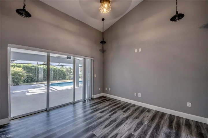 Empty room with a sunroom, lofted ceiling, ceiling fan, and dark wood finished floors