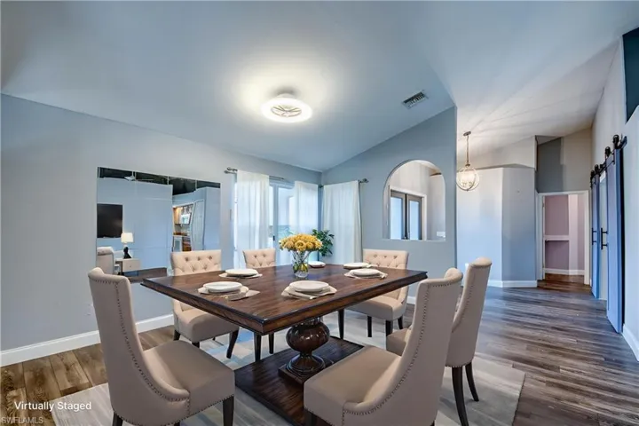Dining room featuring a barn door, vaulted ceiling, and dark wood finished floors