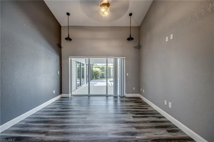Spare room with a textured wall, a high ceiling, and dark wood-style flooring