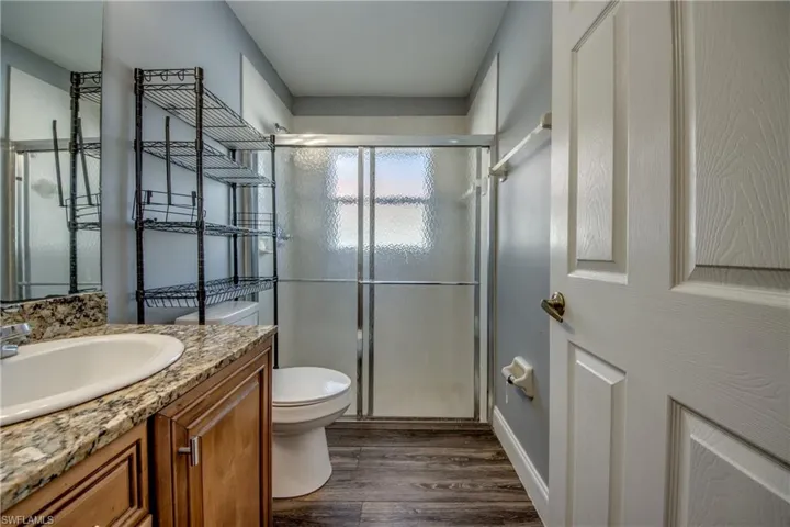 Bathroom with vanity, a stall shower, and dark wood finished floors