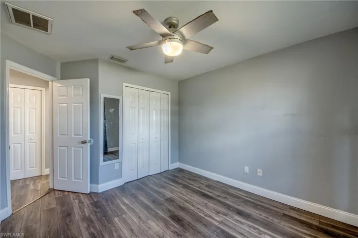 Unfurnished bedroom featuring a closet, dark wood-style flooring, and a ceiling fan