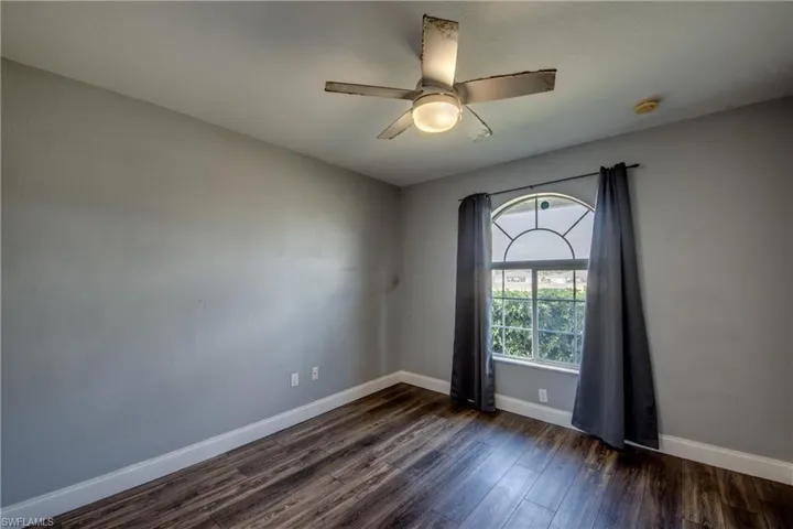 Empty room with dark wood finished floors and ceiling fan