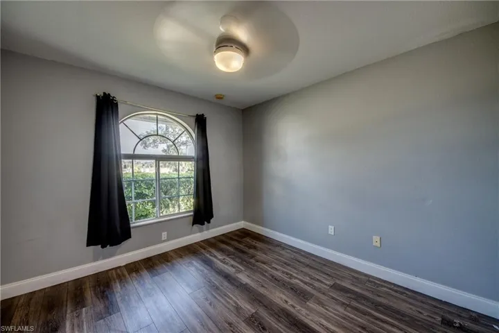 Unfurnished room with dark wood-type flooring and baseboards