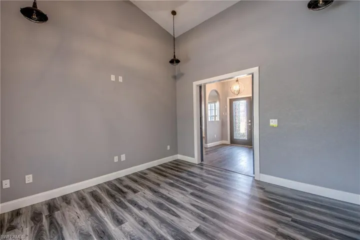 Empty room with dark wood finished floors, vaulted ceiling, and arched walkways