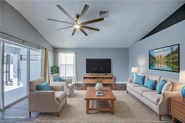 Living room with vaulted ceiling, a ceiling fan, and wood finished floors