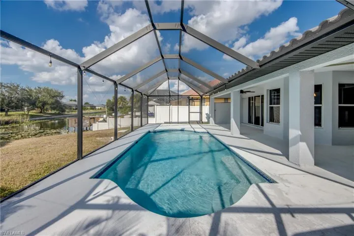 View of pool featuring a sunroom, a lanai, a water view, and patio surround