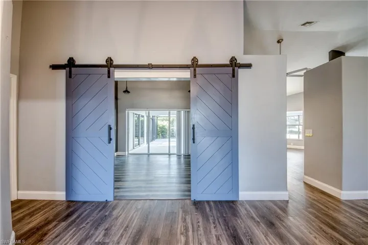 Spare room featuring a high ceiling, dark wood-style floors, healthy amount of natural light, and a barn door