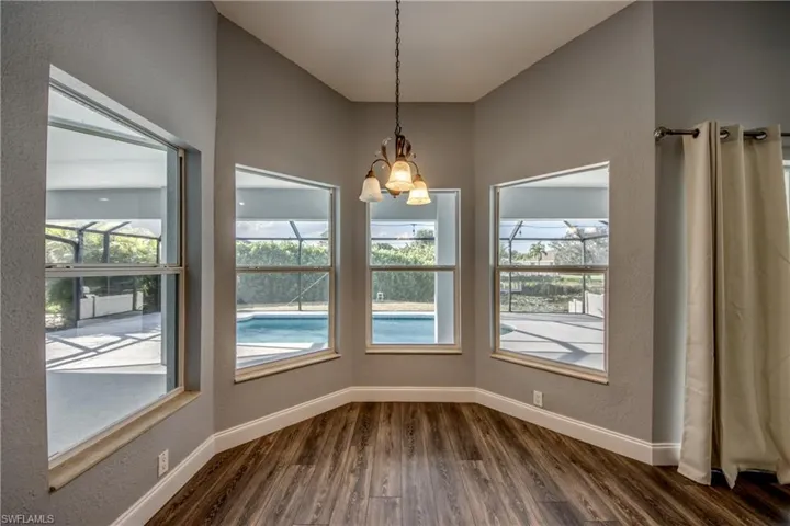 Unfurnished dining area featuring a textured wall, hanging lights, and dark wood finished floors