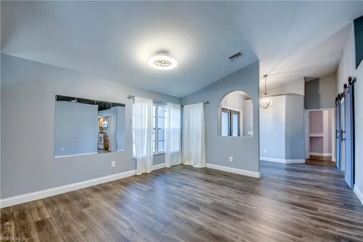 Spare room with lofted ceiling, a barn door, and dark wood-type flooring