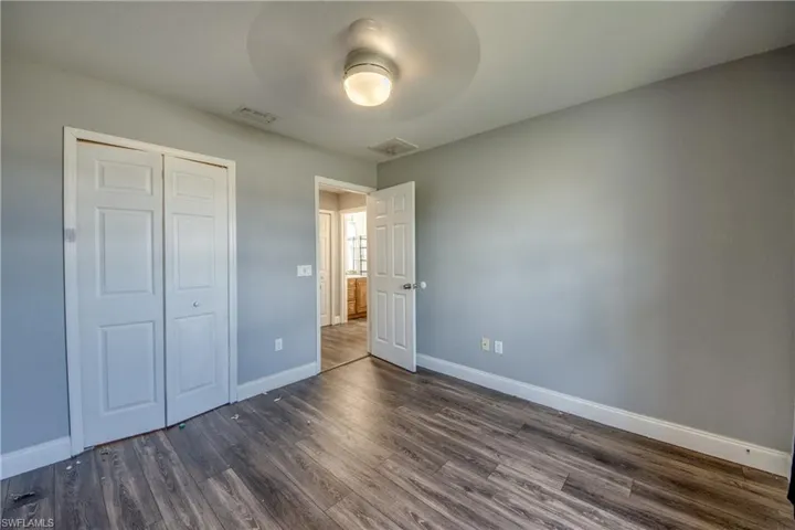 Unfurnished bedroom featuring dark wood-style flooring, a closet, and a ceiling fan