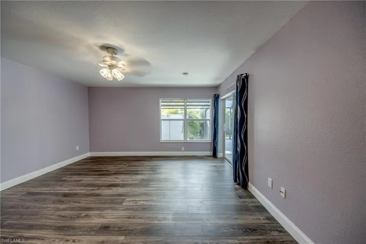 Empty room with dark wood-type flooring, ceiling fan, a textured ceiling, and a textured wall