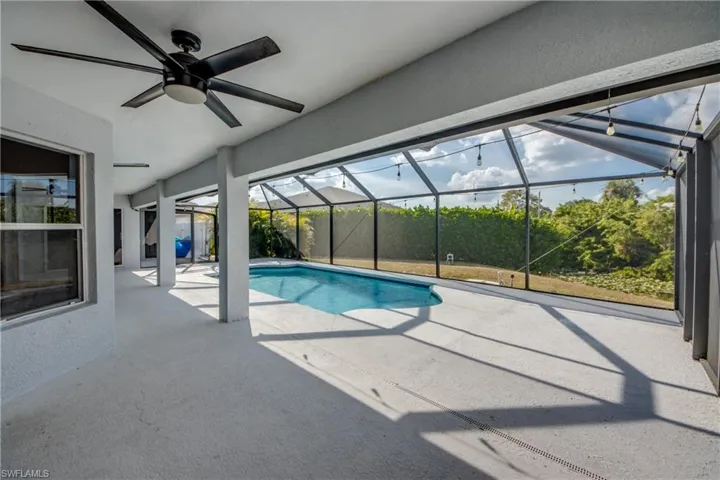 Outdoor pool featuring a patio area, a sunroom, and glass enclosure