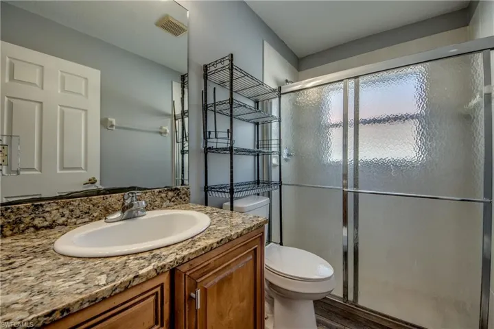 Bathroom featuring a shower stall, vanity, and dark wood-type flooring
