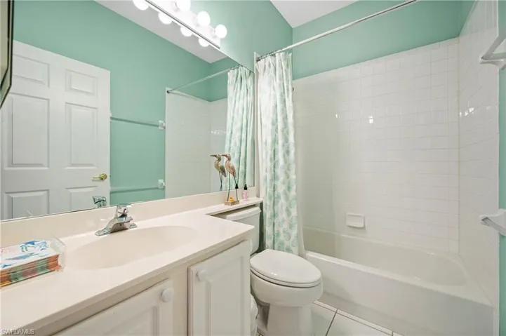 Full bath with shower / bath combination with curtain, tile patterned flooring, and vanity