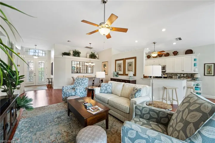 Living room with a chandelier, wood finished floors, a ceiling fan, french doors, and recessed lighting