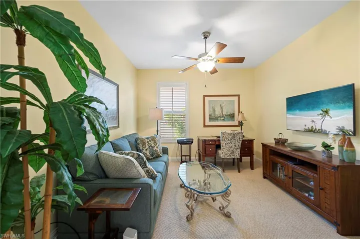 Living area featuring light carpet, an office area, and a ceiling fan
