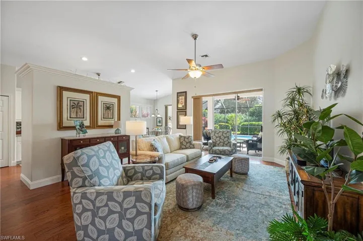 Living room with wood finished floors, a ceiling fan, recessed lighting, and lofted ceiling