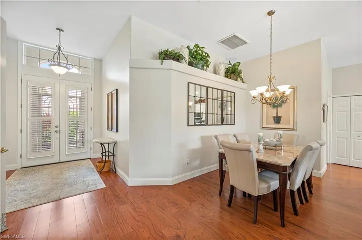 Dining space featuring a chandelier, wood finished floors, high vaulted ceiling, and french doors
