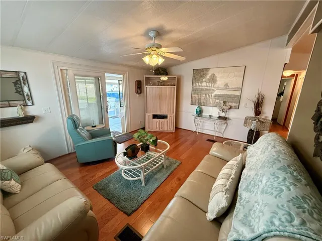 Living area with wood finished floors, a ceiling fan, and vaulted ceiling